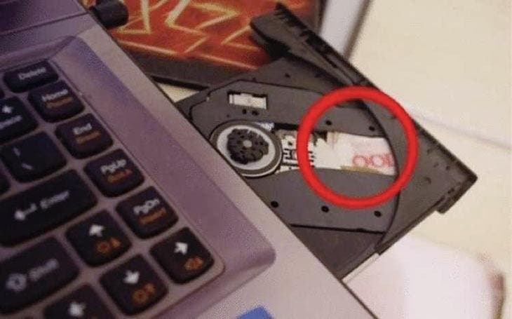 Ein Geldschein, der im CD-Laufwerk eines Computers versteckt ist