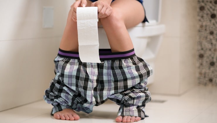 Junger Mann sitzt im Badezimmer