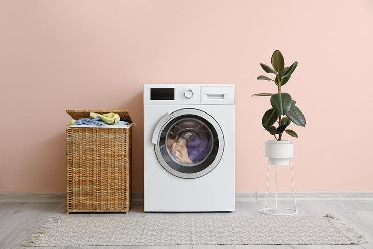 Wie kann man mit weißem Essig in der Waschmaschine Geld sparen? 2 Waschmaschine neben einem Wäschekorb