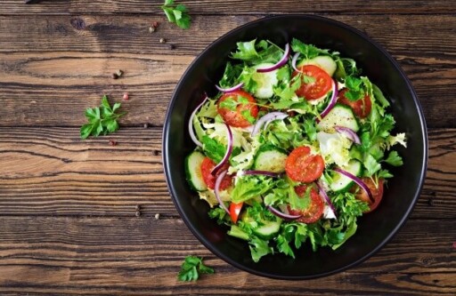 Salad from tomatoes, cucumber, red onions and lettuce leaves. healthy summer vitamin menu. vegan vegetable food. vegetarian dinner table. top view. flat lay Free Photo